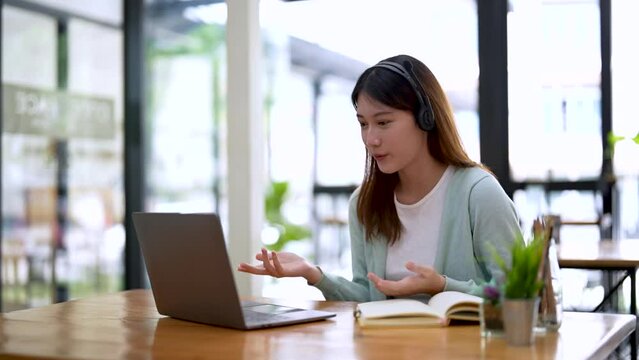 Asian girl college student using laptop computer watching distance online learning seminar class, remote university webinar or having virtual classroom meeting in university creative space