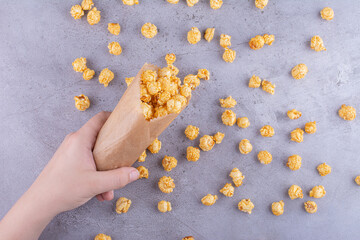 A hand spilling out a pack of caramel coated popcorn on marble background