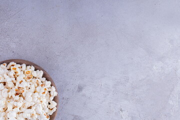 Wooden bowl full of crunchy popcorn on marble background