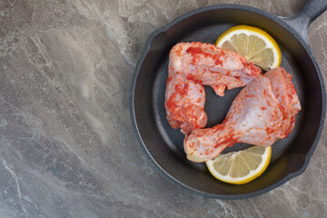 Raw chicken meat with spices and lemon on dark pan