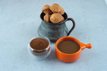 Coffee, ground coffee and cakes on blue background