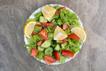 Vegetable salad with slices of lemon on white plate
