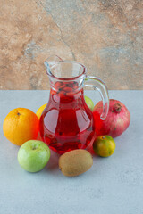 Jar of juice and fresh vegetables on marble background