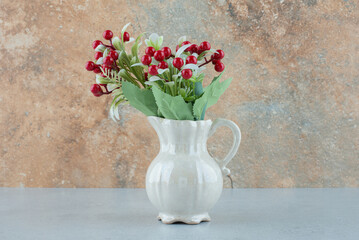 Artificial flowers with berries on blue table