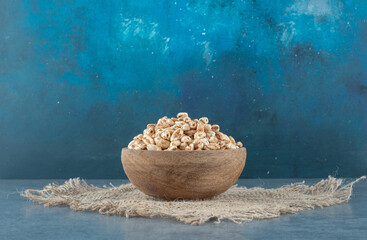 Wooden resting on a cloth piece, filled with a heap of flakes on blue background
