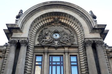 Architectural details of CEC Palace facade on Calea Victoriei boulevard in center of Bucharest. Semicircular pediment with stone sculpture depicting Mercury and Demetra deities
