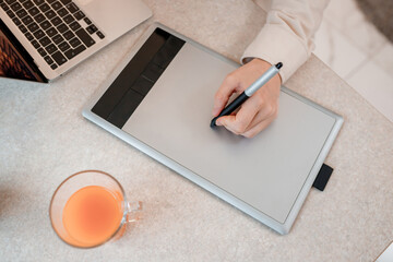Close up of female designer works in home office drawing on graphic tablet. Freelancer working on project, watching movie on computer, studying, blogging, relaxing and chatting online