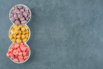 Triple-serving plate of assorted popcorn candy flavors on marble background