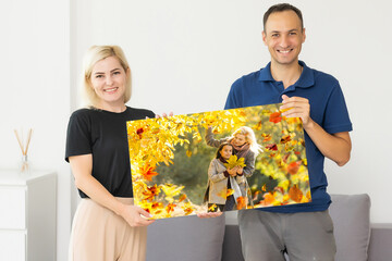 family holding photo canvas with autumn. couple with canvas.