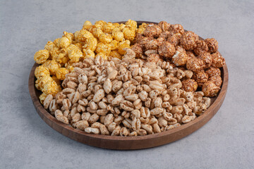 Coated popcorn candies and flakes on a tray on marble background