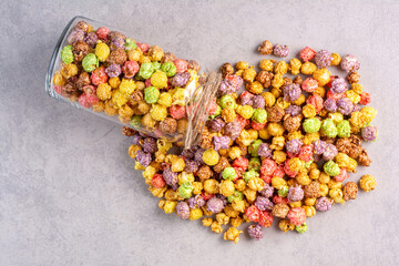 Small jar of popcorn candy spilled over on marble background