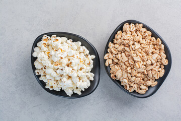 Bowls of popcorn and flakes on marble background