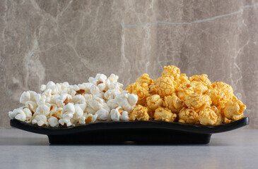 A platter of popcorn candy and salty popcorn on marble background