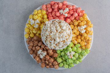 A large platter of coated popcorn candy with a bowl of popcorn in the middle on marble background