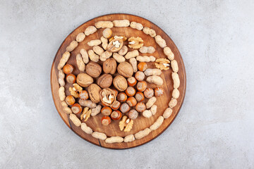 Different nut types arranged on a wooden board on marble background