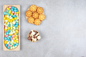 An flavorful serving of popcorn candies, cookies and chocolate mushrooms on marble background