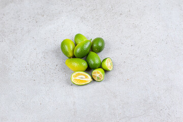 Whole and sliced kumquats placed on marble background