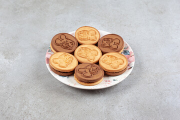 Flavorous, decorated cookies on decorated plate on marble background