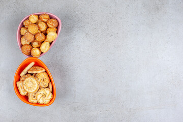Small cookies piled in two bowls on marble background