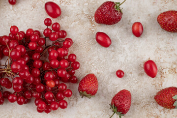 Scattered cluster of redcurrant, hips and strawberries on marble background