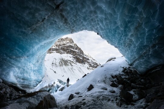 Ice cave exploration with a silhouette of a hiker in Arolla glacier, Valais Switzerland