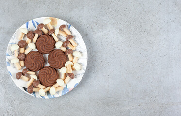 Cookies surrounded by chocolate mushrooms on a plate on marble background