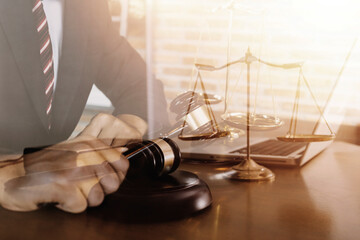 Justice and law concept.Male judge in a courtroom with the gavel, working with, computer and docking keyboard, eyeglasses, on table in morning light