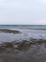 Wet sand. Gloomy landscape. The nature of the Europe. The coast of the Atlantic Ocean. Gray sand beach