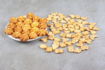 Cookies on a plate next to scattered biscuits on marble background