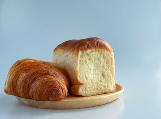Side view of a Plain croissant and Japanese soft and fluffy milk bread bun on a wooden tray, café mood tone, chic color, warm tone, object and still life, left side