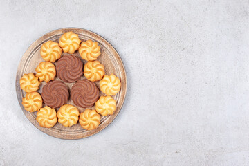 Cookies decoratively aligned on wooden board on marble background