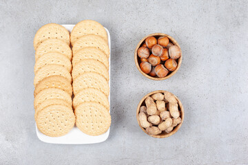 Plate of biscuits next to bowls of hazelnut and chocolate mushrooms on marble background