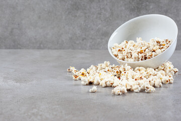 Bowl of popcorn scattered on marble background