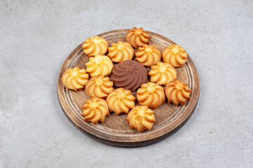 Cookies decoratively aligned on wooden board on marble background