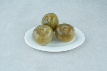 Fermented green tomatoes on white plate