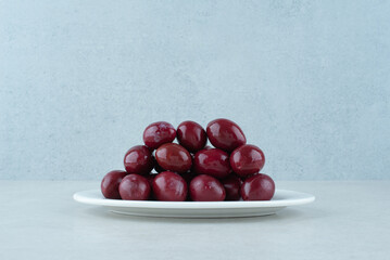 Pickled cornel cherries on white plate