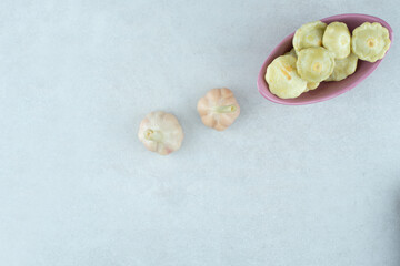 Various pickled fruits in pink bowl with fresh garlic