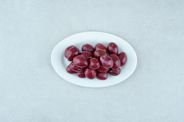 Pickled cornel cherries on white plate