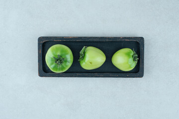 Pickled green tomatoes on black plate