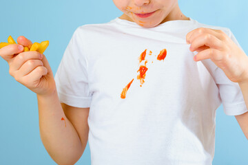 A boy's hand showing a dirty sauce stain on his clothes. Isolated on blue background. A child...