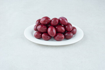 Pickled cornel cherries on white plate