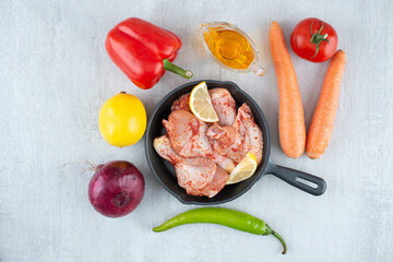 Pan of seasoned chicken, oil and vegetables on stone surface