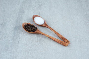 Salt and pepper grains on wooden spoons