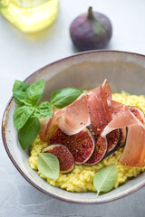 Close-up of risotto with cured ham, fresh fig fruit and green basil, vertical shot, selective focus