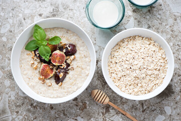 Bowls with oatmeal and oat flakes on a light-brown granite background, top view, horizontal shot