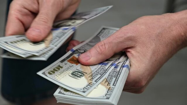 businessman starts counting a stack of hundred dollar bills. close-up of men's hands counting a stack of cash. the concept of investment, money exchange, bribes or corruption. selective focus.