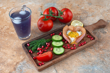 A wooden board with omelet and vegetables with cup of drink