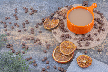 Cup of milk coffee with coffee beans and oranges