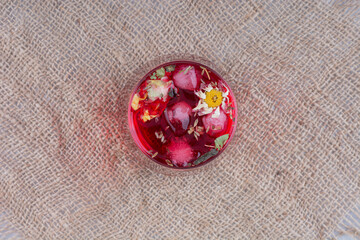 A glass of red juice on burlap with flowers