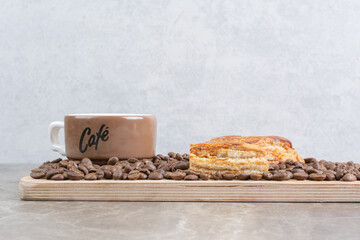 Cup of coffee, cookies and coffee beans on wooden plate